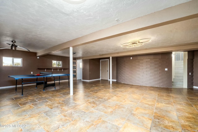 4939 E River Rd, Tucson, AZ 85718 - rec room featuring baseboards, a textured ceiling, a ceiling fan, and brick wall