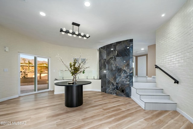 4939 E River Rd, Tucson, AZ 85718 - spare room featuring light wood-type flooring, baseboards, stairway, and brick wall