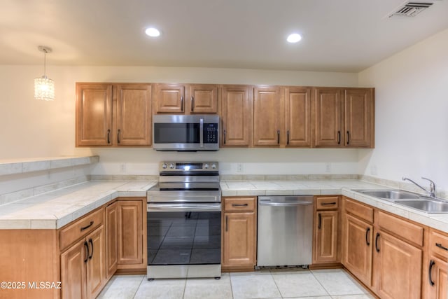 6255 N Camino Pimeria Alta Apt 81, Tucson, AZ 85718 - kitchen featuring appliances with stainless steel finishes, a sink, recessed lighting, brown cabinetry, and light tile patterned flooring