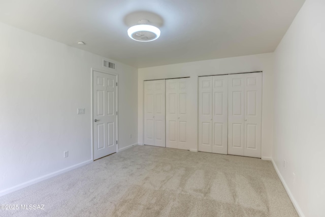6255 N Camino Pimeria Alta Apt 81, Tucson, AZ 85718 - unfurnished bedroom featuring carpet floors, two closets, and baseboards