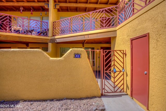 6255 N Camino Pimeria Alta Apt 81, Tucson, AZ 85718 - view of exterior entry with stucco siding, a balcony, and a gate