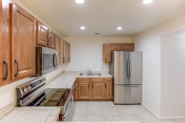 6255 N Camino Pimeria Alta Apt 81, Tucson, AZ 85718 - kitchen with appliances with stainless steel finishes, tile countertops, a sink, recessed lighting, and brown cabinetry