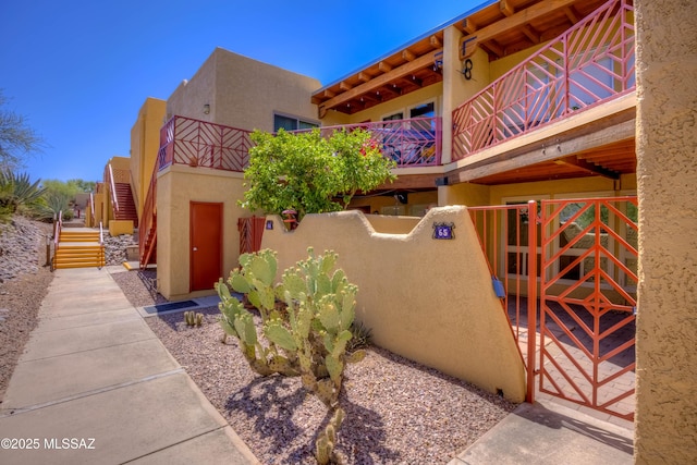 6255 N Camino Pimeria Alta Apt 65, Tucson, AZ 85718 - view of property exterior with stucco siding, stairway, a gate, and a balcony