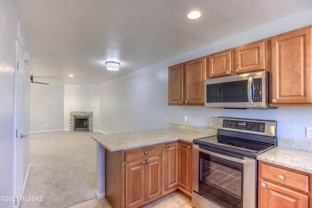6255 N Camino Pimeria Alta Apt 65, Tucson, AZ 85718 - kitchen with stainless steel appliances, a peninsula, light stone counters, a fireplace, and recessed lighting