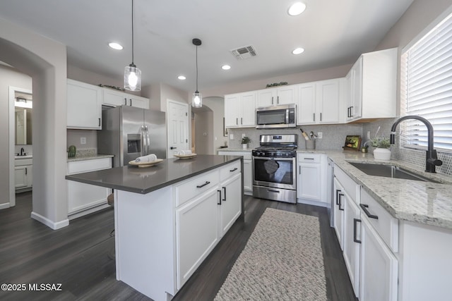 Tucson, AZ 85748 - kitchen featuring stainless steel appliances, a sink, arched walkways, dark wood-style floors, and tasteful backsplash