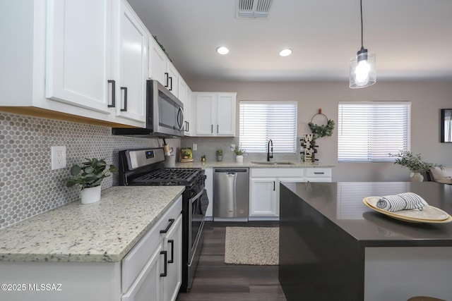 Tucson, AZ 85748 - kitchen featuring appliances with stainless steel finishes, a sink, white cabinets, tasteful backsplash, and decorative light fixtures