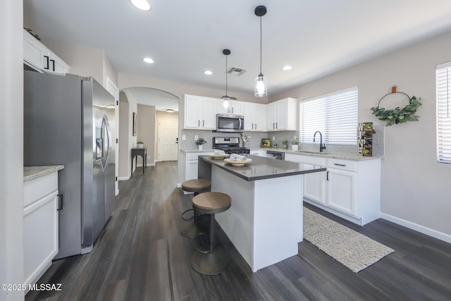 Tucson, AZ 85748 - kitchen with appliances with stainless steel finishes, arched walkways, dark wood-style floors, a kitchen island, and a sink