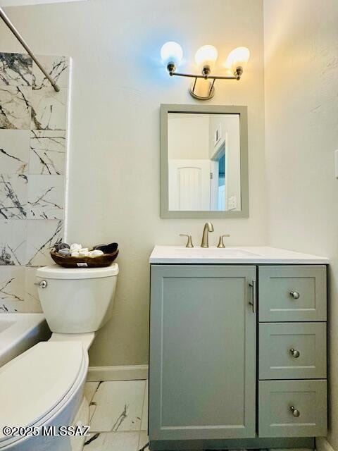 7122 E Eastland St, Tucson, AZ 85710 - bathroom with vanity, marble look tile flooring, toilet, baseboards, and bathtub / shower combination