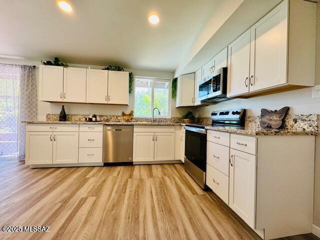 7122 E Eastland St, Tucson, AZ 85710 - kitchen featuring stainless steel appliances, light wood-style floors, white cabinetry, light stone countertops, and a sink