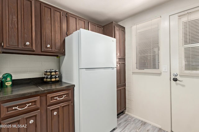 134 S Paseo Quinta Unit A, Green Valley, AZ 85614 - kitchen featuring freestanding refrigerator, dark countertops, light wood finished floors, tasteful backsplash, and dark brown cabinetry