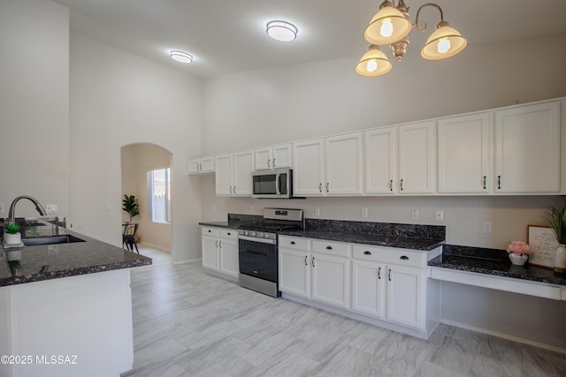 7663 W Creosote Spring Ct, Tucson, AZ 85743 - kitchen featuring appliances with stainless steel finishes, a sink, arched walkways, high vaulted ceiling, and white cabinetry