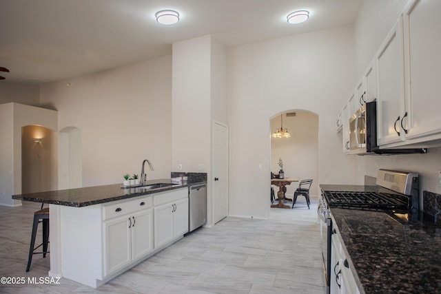 7663 W Creosote Spring Ct, Tucson, AZ 85743 - kitchen featuring appliances with stainless steel finishes, arched walkways, a sink, a peninsula, and a breakfast bar