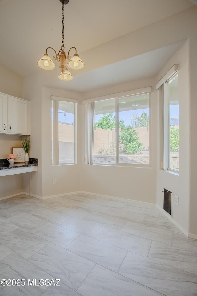 7663 W Creosote Spring Ct, Tucson, AZ 85743 - unfurnished dining area with plenty of natural light, a chandelier, baseboards, and light marble finish floors