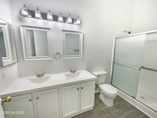 8233 E Sundew Dr, Tucson, AZ 85710 - full bathroom featuring double vanity, an enclosed shower, toilet, and wood finished floors