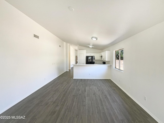 8233 E Sundew Dr, Tucson, AZ 85710 - unfurnished living room featuring lofted ceiling, dark wood-style floors, and baseboards