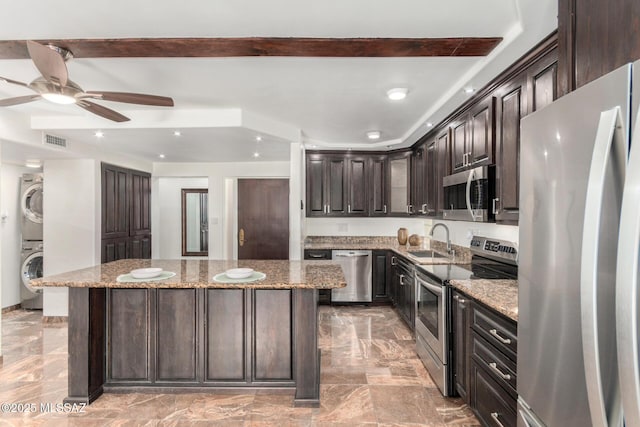3940 E Timrod St Unit 118, Tucson, AZ 85711 - kitchen with stainless steel appliances, estacked washer and dryer, a center island, dark brown cabinets, and a ceiling fan