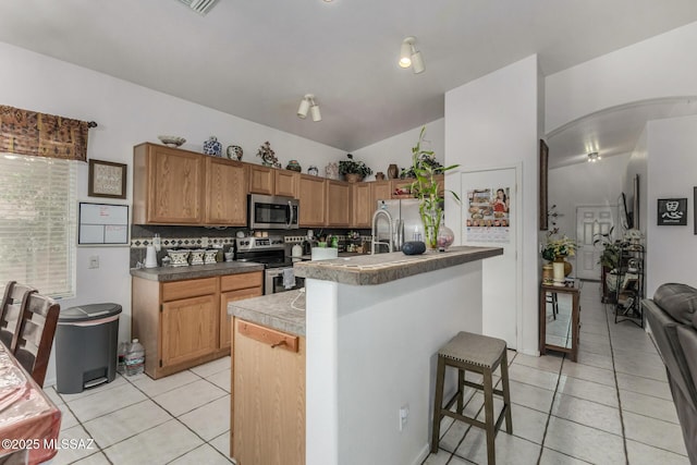 7157 W Odyssey Way, Tucson, AZ 85743 - kitchen with stainless steel appliances, light tile patterned flooring, decorative backsplash, vaulted ceiling, and a kitchen bar