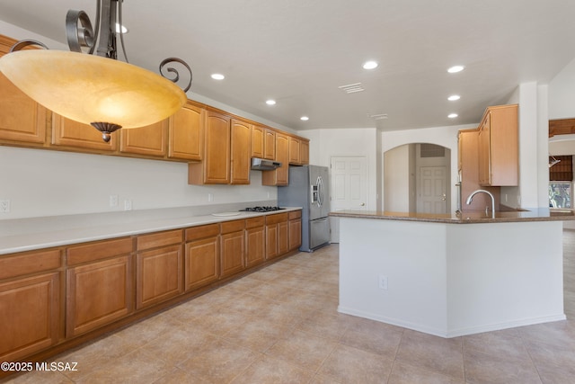 14243 E Whisper Trl, Vail, AZ 85641 - kitchen with stainless steel fridge, under cabinet range hood, recessed lighting, black gas cooktop, and arched walkways