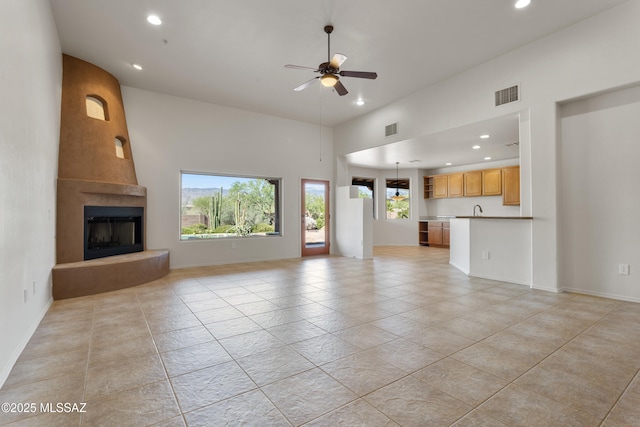 14243 E Whisper Trl, Vail, AZ 85641 - unfurnished living room with recessed lighting, a ceiling fan, a fireplace, light tile patterned flooring, and a high ceiling