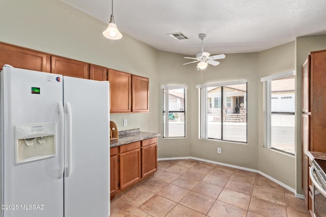 8172 N Streamside Ave, Tucson, AZ 85741 - kitchen featuring white refrigerator with ice dispenser, ceiling fan, brown cabinets, and healthy amount of natural light
