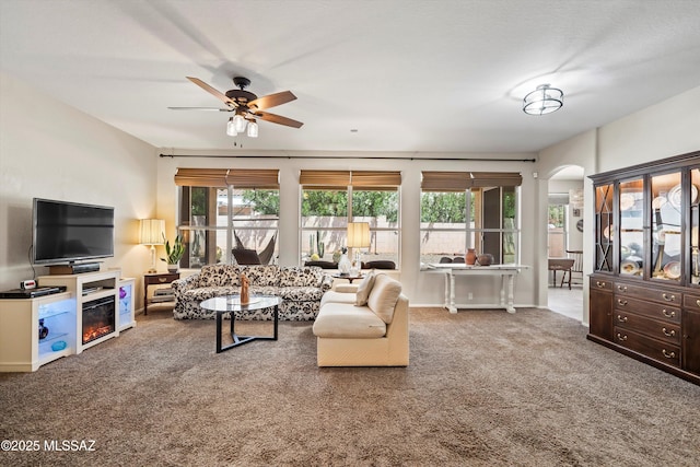 9860 N Western Sky Pl, Tucson, AZ 85742 - carpeted living area featuring arched walkways, a ceiling fan, and healthy amount of natural light