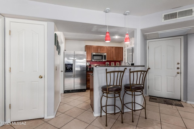 5751 N Kolb Rd Unit 25203, Tucson, AZ 85750 - kitchen with stainless steel appliances, light tile patterned floors, a breakfast bar area, dark countertops, and brown cabinetry