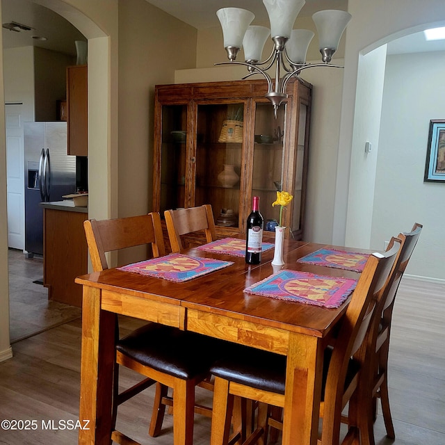 536 W Deerview Ct, Green Valley, AZ 85614 - dining area featuring arched walkways, a chandelier, and wood finished floors