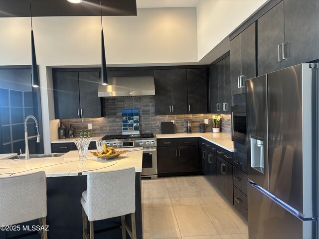 12710 N Sonoran Preserve Blvd Lot 24, Marana, AZ 85658 - kitchen featuring stainless steel appliances, a sink, dark cabinetry, backsplash, and wall chimney range hood