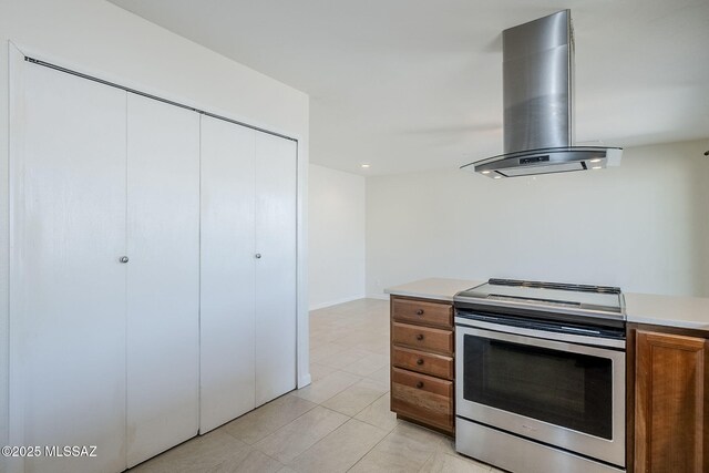 9415 E Simon Pl, Tucson, AZ 85710 - kitchen with extractor fan, stainless steel range with electric cooktop, brown cabinetry, light countertops, and light tile patterned floors