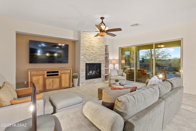 12475 N Faraway Wash Trl, Marana, AZ 85658 - living room featuring a ceiling fan, light tile patterned floors, and a stone fireplace