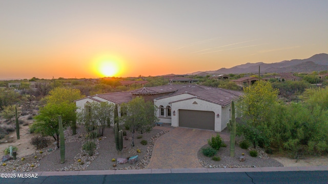 12475 N Faraway Wash Trl, Marana, AZ 85658 - mediterranean / spanish house with a garage, decorative driveway, a tiled roof, a mountain view, and stucco siding