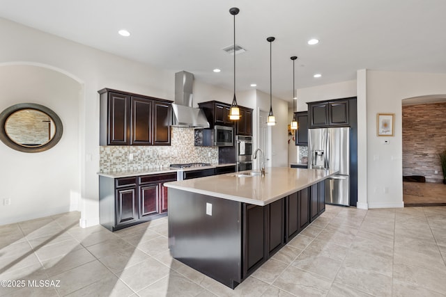 12475 N Faraway Wash Trl, Marana, AZ 85658 - kitchen with stainless steel appliances, wall chimney exhaust hood, arched walkways, light countertops, and decorative backsplash