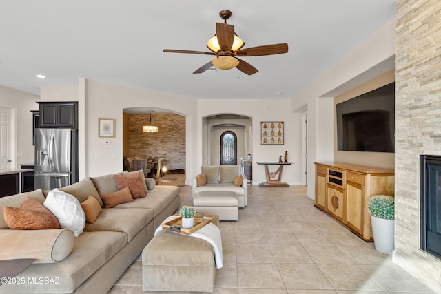 12475 N Faraway Wash Trl, Marana, AZ 85658 - living room with arched walkways, ceiling fan, light tile patterned floors, and a fireplace