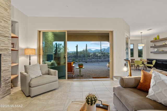 12475 N Faraway Wash Trl, Marana, AZ 85658 - living room featuring built in features, light tile patterned flooring, a mountain view, and a fireplace