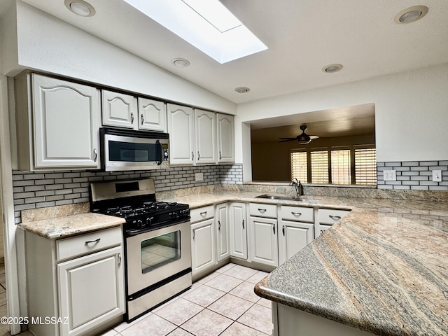 7621 N Placita De Los Amigos, Tucson, AZ 85704 - kitchen with appliances with stainless steel finishes, decorative backsplash, vaulted ceiling, ceiling fan, and a skylight