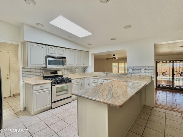 7621 N Placita De Los Amigos, Tucson, AZ 85704 - kitchen featuring stainless steel appliances, a peninsula, backsplash, vaulted ceiling, and a skylight