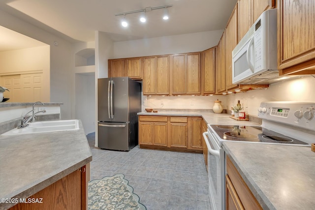 8191 N White Stallion Pl, Tucson, AZ 85743 - kitchen with white appliances, light tile patterned floors, track lighting, arched walkways, and light countertops