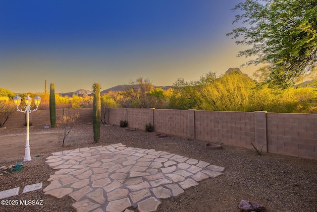 8191 N White Stallion Pl, Tucson, AZ 85743 - patio terrace at dusk featuring a fenced backyard, a patio area, and a mountain view