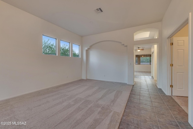 8191 N White Stallion Pl, Tucson, AZ 85743 - empty room featuring arched walkways, ceiling fan, tile patterned flooring, and carpet floors