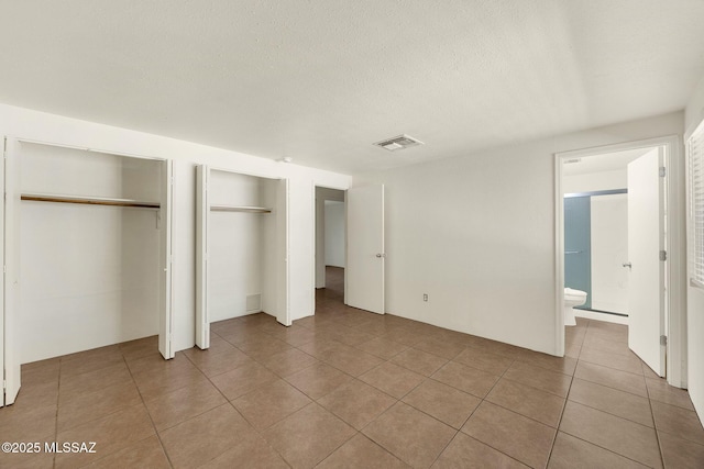 2520 W Vereda De Las Flores, Tucson, AZ 85746 - unfurnished bedroom with two closets, light tile patterned floors, and a textured ceiling