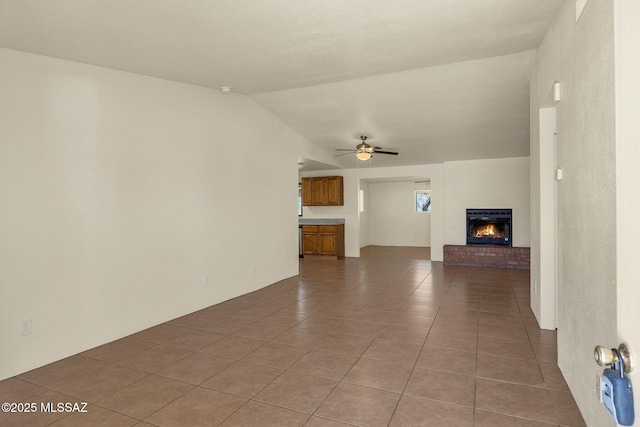 2520 W Vereda De Las Flores, Tucson, AZ 85746 - unfurnished living room with tile patterned flooring, lofted ceiling, ceiling fan, and a brick fireplace