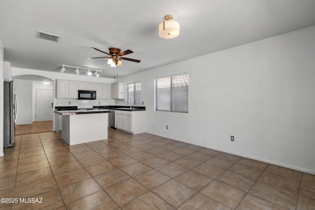 9969 E Apache Rain Dr, Tucson, AZ 85748 - kitchen featuring stainless steel appliances, arched walkways, a ceiling fan, a kitchen island, and white cabinets