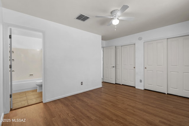 9969 E Apache Rain Dr, Tucson, AZ 85748 - unfurnished bedroom featuring multiple closets, wood finished floors, connected bathroom, and a ceiling fan
