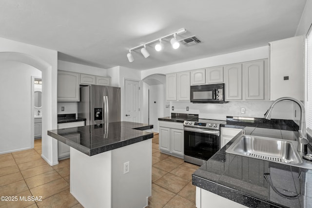 9969 E Apache Rain Dr, Tucson, AZ 85748 - kitchen featuring appliances with stainless steel finishes, arched walkways, tile counters, and light tile patterned floors