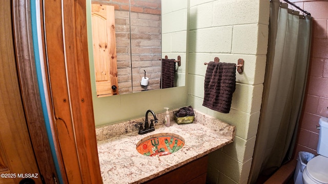 1094 N Pomerene Rd, Benson, AZ 85602 - bathroom with toilet, curtained shower, vanity, and concrete block wall