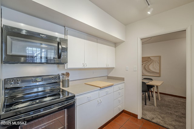 3940 E Timrod St Unit 226, Tucson, AZ 85711 - kitchen with black appliances, white cabinetry, light countertops, rail lighting, and dark tile patterned flooring