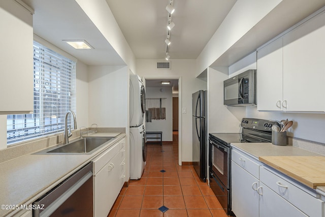 3940 E Timrod St Unit 226, Tucson, AZ 85711 - kitchen with black appliances, stacked washer and clothes dryer, a sink, and white cabinets