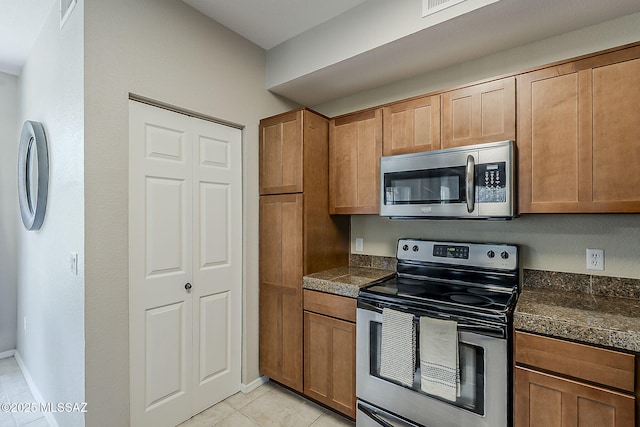 1500 E Pusch Wilderness Dr Unit 15205, Oro Valley, AZ 85737 - kitchen with stainless steel appliances, light tile patterned flooring, and brown cabinetry
