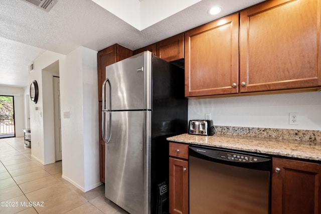 7255 E Snyder Rd Unit 9103, Tucson, AZ 85750 - kitchen with appliances with stainless steel finishes, light tile patterned floors, a textured ceiling, light stone countertops, and brown cabinetry