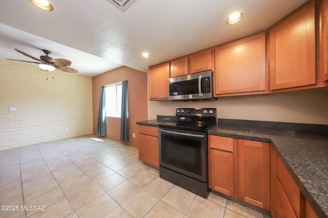 1641 S San Carla, Green Valley, AZ 85614 - kitchen featuring black electric range oven, stainless steel microwave, brick wall, dark countertops, and brown cabinetry